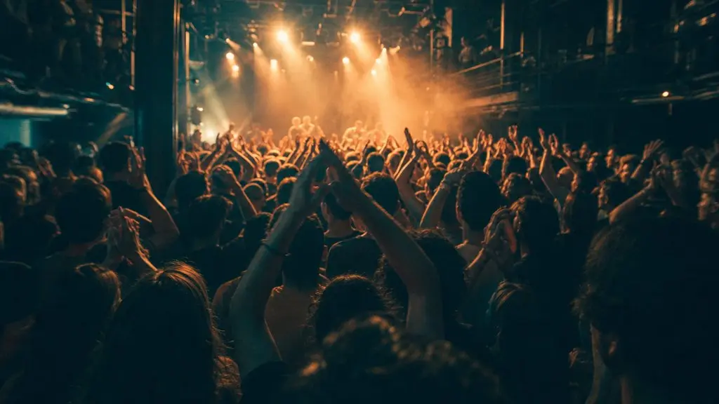 A packed music venue with hands in the air